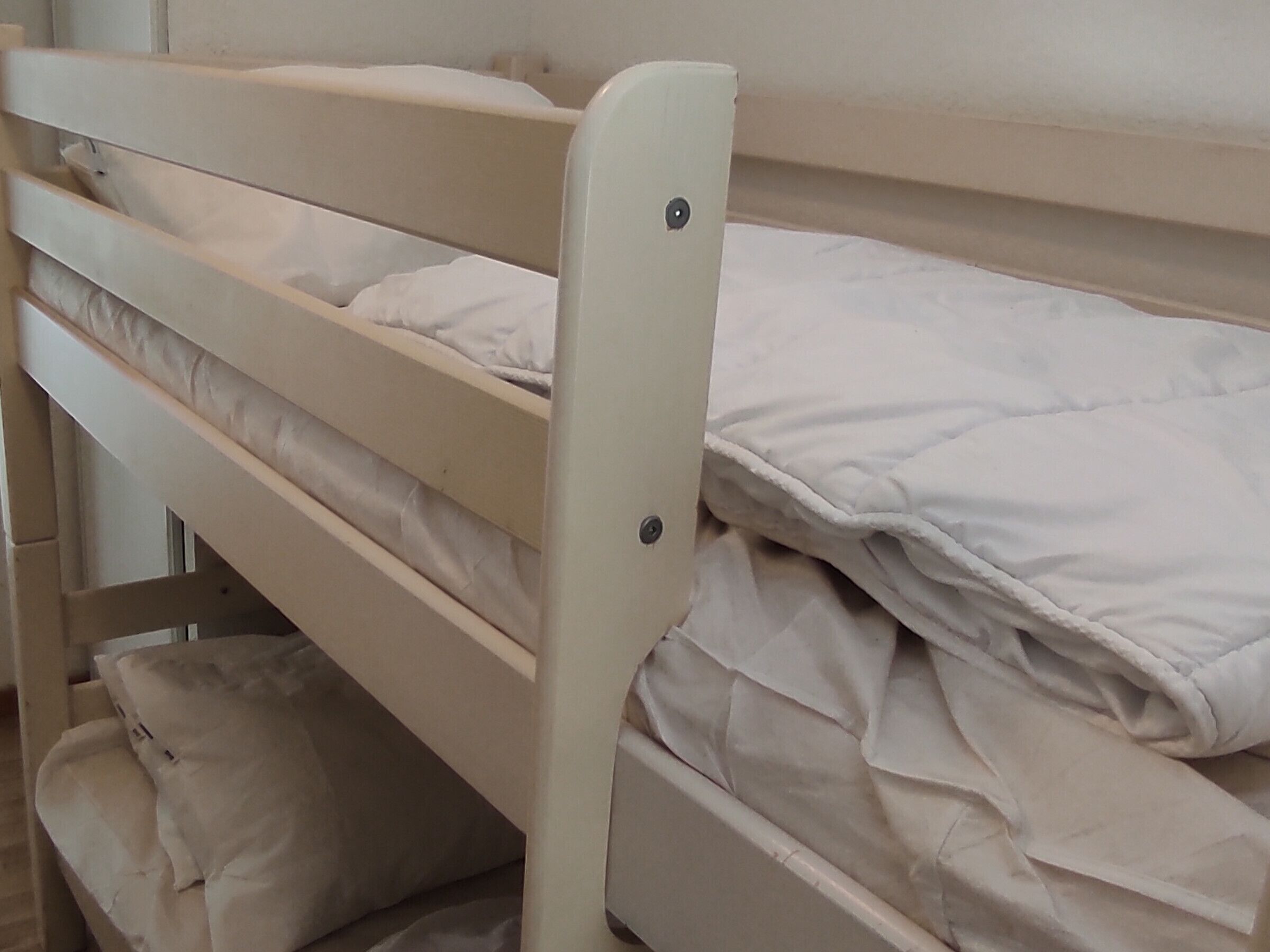 Una cama litera con cabecera blanca y colchón.