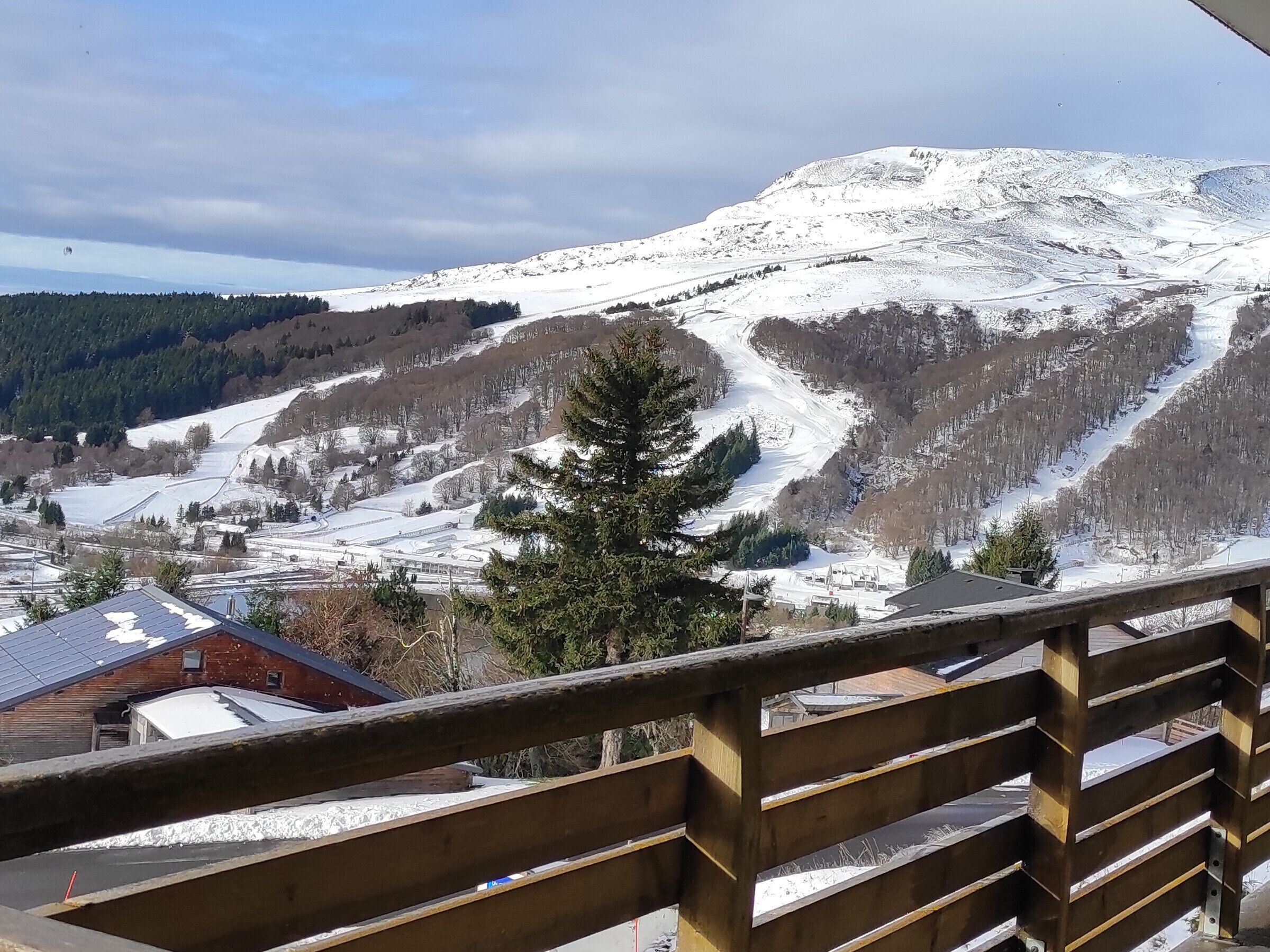 A snowy mountain landscape with a wooden railing in the foreground.