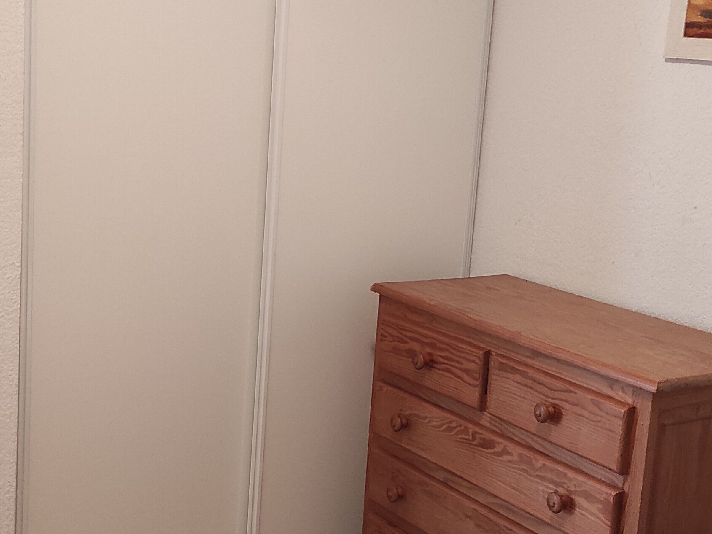 A wooden dresser with three drawers against a plain wall.