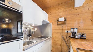 A kitchen with white cabinets, a stainless steel range hood, a sink, and a wooden floor. - Les Gets - 2-Bedroom Apartment Near Slopes with Balcony and Parking (Les Gets)