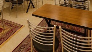 Une salle de conférence dotée de plusieurs tables et chaises, de ventilateurs de plafond, d’appliques murales et d’un élément décoratif mural.