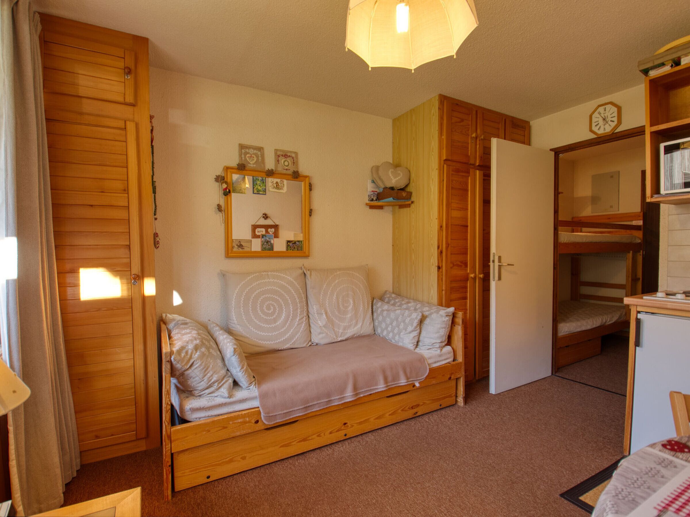 Una habitación acogedora con un sofá de madera, una mesita, una cama litera y un espejo en la pared.