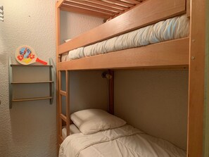 Ein Stockbett mit einer Halterung, ein Regal mit einem Dekorationsobjekt und ein Kissen.