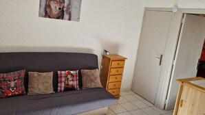 Ein Wohnzimmer mit grauem Sofa, einem Holzschrank und einer Tür.