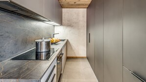Una cocina moderna con armarios grises, techo de madera y encimera de mármol.