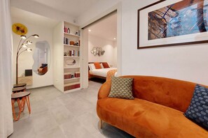 A modern living room with an orange sofa, a bookshelf, and a dining area with a table and chairs. - CASA INDIPENDENTE A PRATI (ROMA)