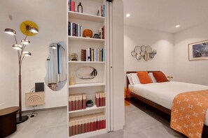 A modern bedroom with a bed, a bookshelf, a desk with a lamp, and a mirror. - CASA INDIPENDENTE A PRATI (ROMA)
