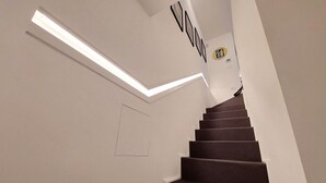 Modernilla designilla varustetut portaat, joissa on valaisin ja seinällä oleva kehystetty taulu.