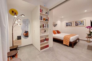 A modern bedroom with a bed, a bookshelf, a mirror, and a desk. - CASA INDIPENDENTE A PRATI (ROMA)