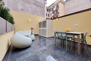 A modern outdoor patio with a dining table and chairs, a white sofa, and a decorative plant. - CASA INDIPENDENTE A PRATI (ROMA)