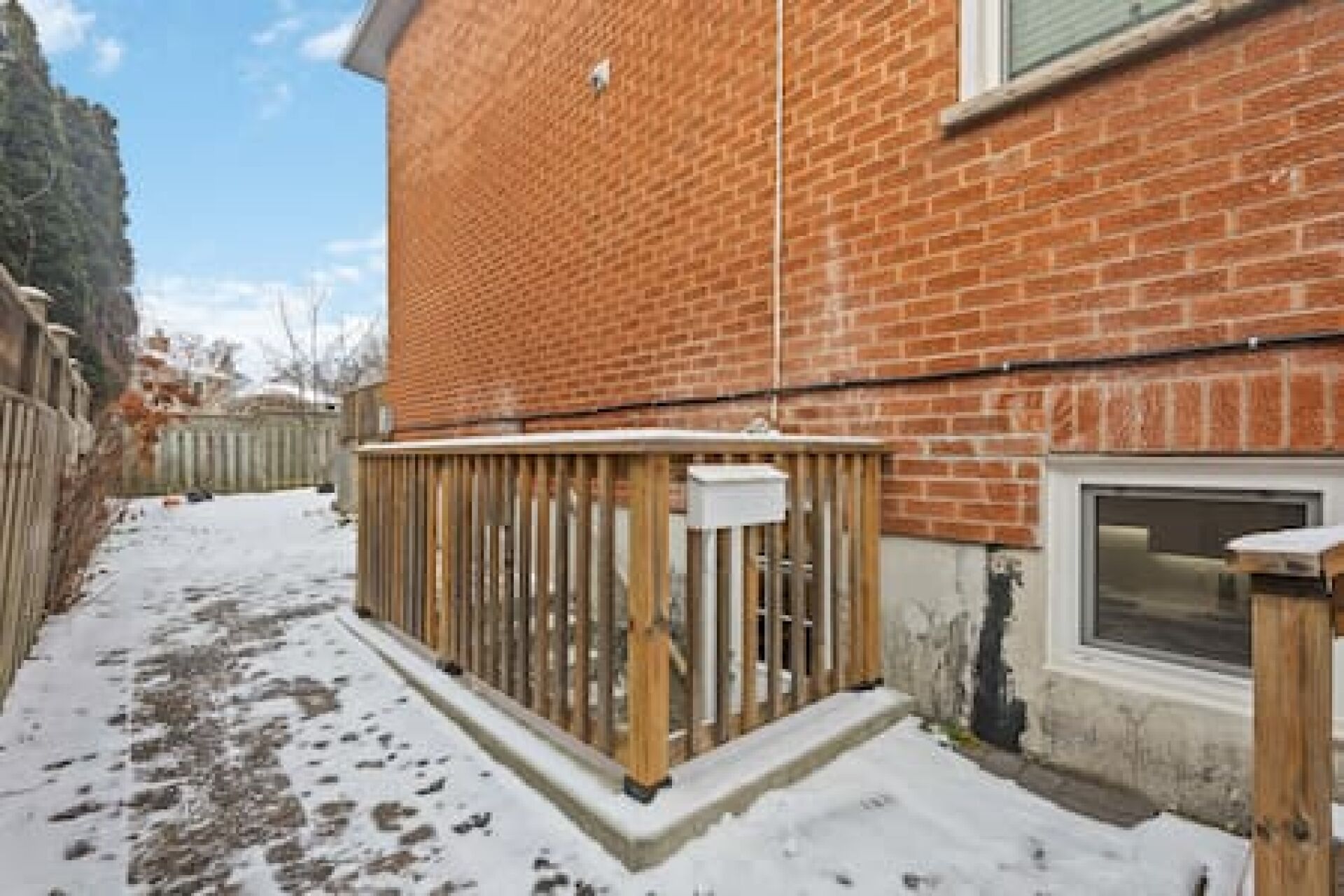 Une maison en briques avec une terrasse en bois et une fenêtre.