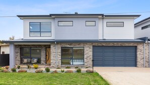 A two-story house with a garage, large windows, and a well-maintained front yard. - Mercer on Port - Your Perfect Portarlington Getaway (Portarlington)