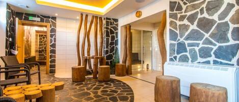 Un vestíbulo con paredes de piedra, muebles de madera y un diseño moderno del techo.