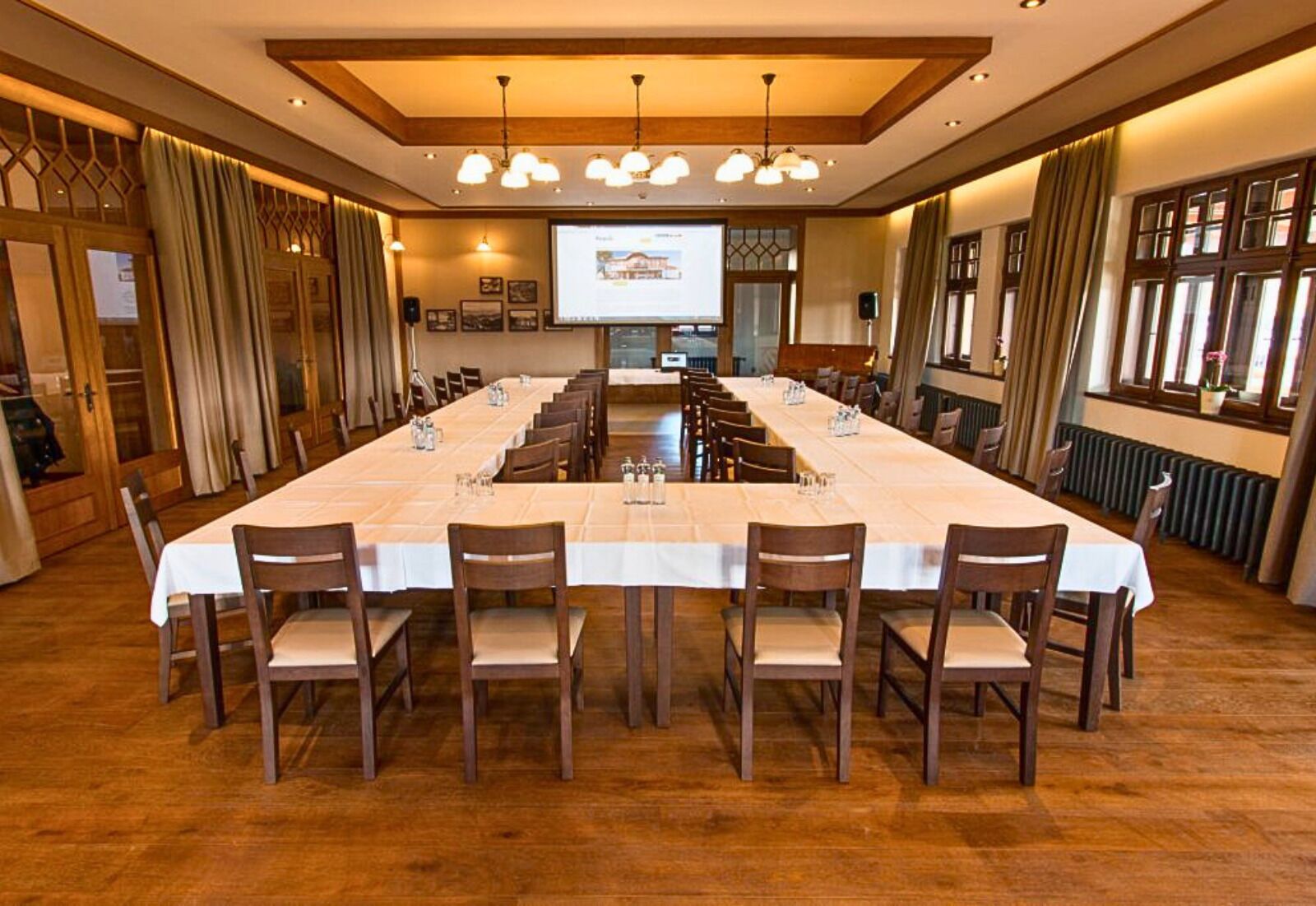 A conference room with a long table, chairs, a projector screen, and a presentation.
