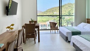 Ein Hotelzimmer mit Balkon, einem Essbereich mit Korbmöbeln und einem Bett mit weißer Bettwäsche.