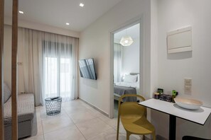 Ein modernes Hotelzimmer mit einem Bett, einem an der Wand montierten Fernseher, einem kleinen Tisch mit einer Schale und einem Sessel.