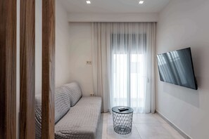 Ein moderner, minimalistischer Raum mit einer Couch, einem runden Beistelltisch und einem an der Wand montierten Fernseher.