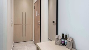 A hotel room with a wooden wardrobe, a mirror, and two wine bottles on a table. - Harma City Living - Street View Standard Apartment (Chania)