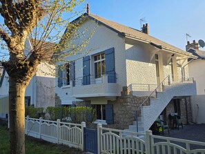 Ein zweistöckiges Haus mit einer Steinaußenfassade, einem Balkon und einem weißen Zaun.