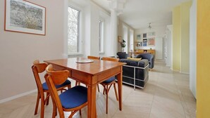 Un'ampia zona giorno con un tavolo e sedie di legno, un divano e una cucina sullo sfondo.