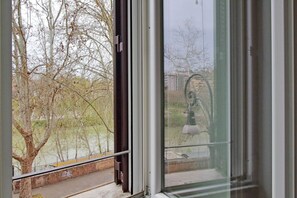 Blick durch ein Fenster auf kahle Bäume und einen Laternenpfahl.