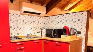 A compact kitchen with red cabinets, a microwave, a kettle, and a toaster. - Cangrande Apartment: city center (Verona)