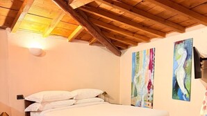 A bedroom with a wooden ceiling, a bed, and two abstract paintings on the wall. - Cangrande Apartment: city center (Verona)