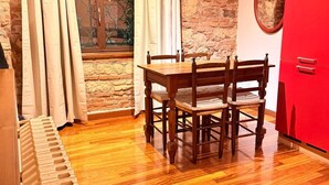 A dining area with a wooden table and chairs, a red cabinet, and a stone wall. - Cangrande Apartment: city center (Verona)