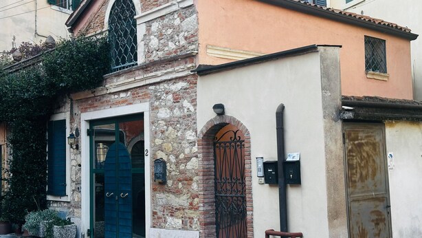 A building with a stone facade, a blue door, and a metal gate. - Cangrande Apartment: city center (Verona)
