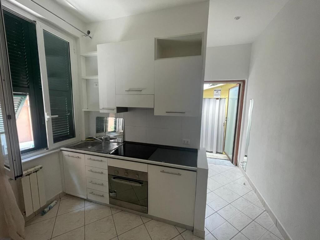 A compact kitchen with white cabinets, a black countertop, and a built-in oven.