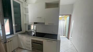 A compact kitchen with white cabinets, a black countertop, and a built-in oven.