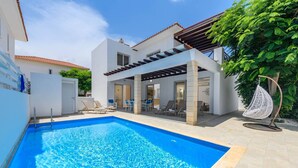 Un'area piscina moderna con piscina blu cristallina, una pergola e posti a sedere all'aperto.
