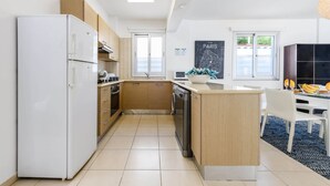 Una cucina moderna con frigorifero, forno e lavastoviglie. È presente un'area pranzo con tavolo e sedie.