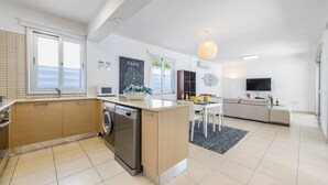 Una cucina moderna con lavastoviglie, un'area pranzo con tavolo e sedie, un divano e una TV.