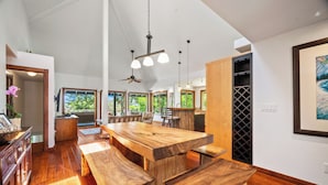 A spacious kitchen with a large wooden island, pendant lighting, and a ceiling fan. - Ohana Kai, Luxe Princeville home w/ AC (Princeville)
