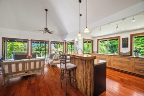 Eine moderne Küche mit Bar, großen Fenstern und Deckenventilator.
