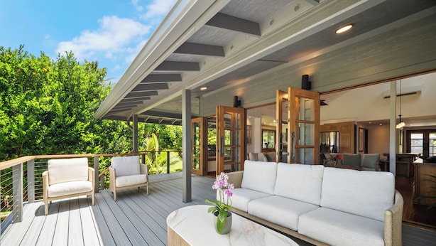 A covered outdoor deck with a sofa, chairs, and a marble coffee table. - Ohana Kai, Luxe Princeville home w/ AC (Princeville)