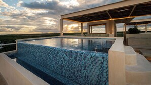 Une piscine dont le bord est revêtu de carrelage, entourée d’une zone abritée offrant une vue sur le paysage.