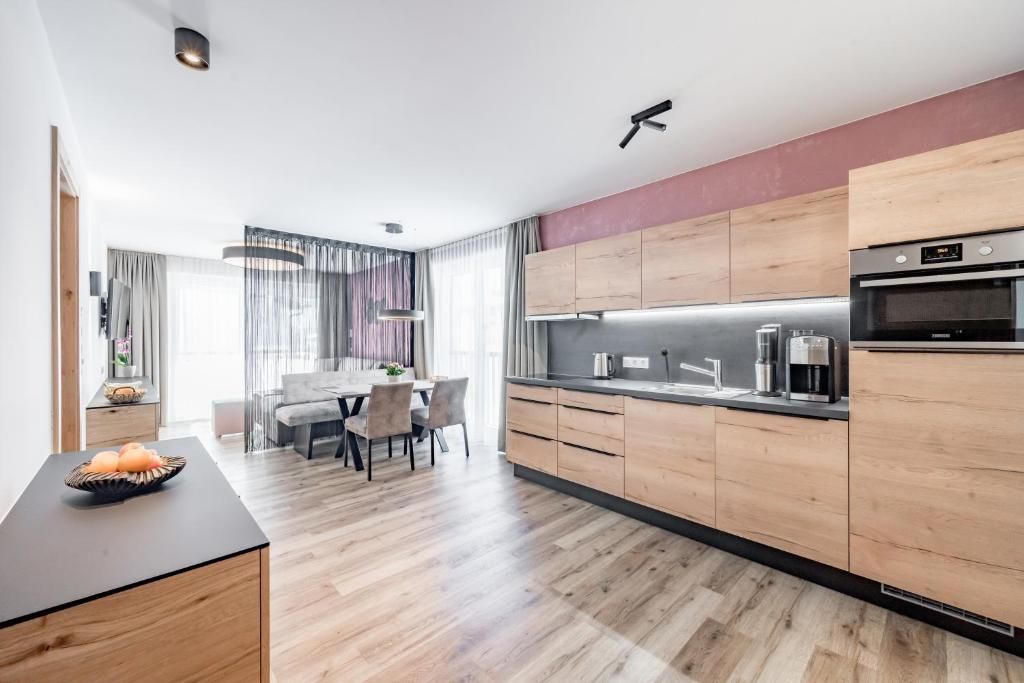 Eine moderne Küche mit Holzausstattung, einem Essbereich mit Tisch und Stühlen sowie einem sichtbaren Backofen.
