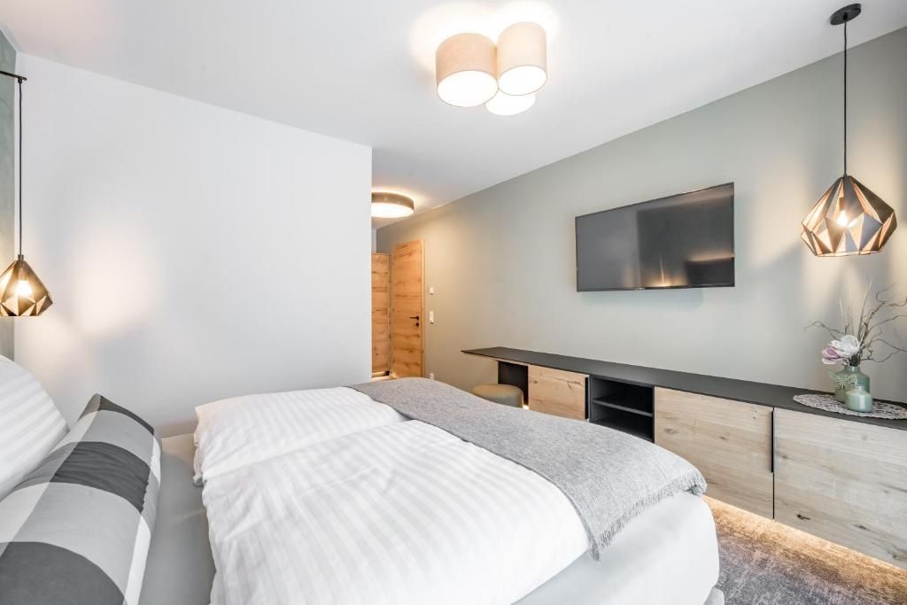 Ein modernes Schlafzimmer mit einem Bett, Nachttischen, einem Fernseher und einem Holzschrank.