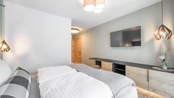 Ein modernes Schlafzimmer mit einem Bett, Nachttischen, einem Fernseher und einem Holzschrank.