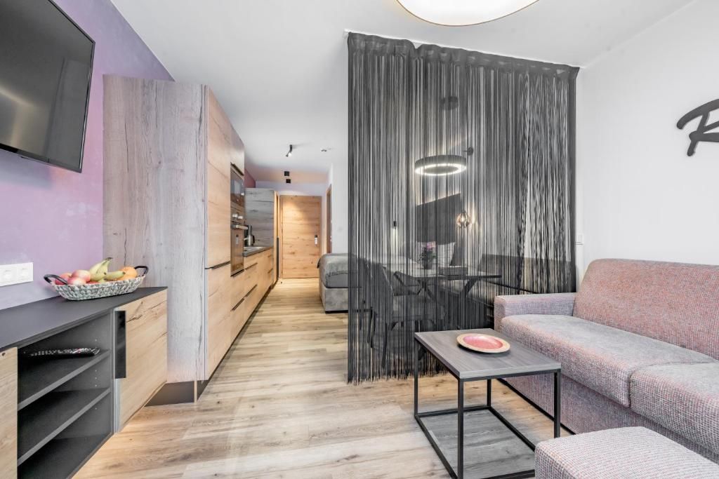 A modern living space with a flat-screen TV, a dining area with a table and chairs, and a sofa.