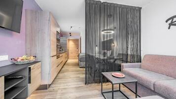 A modern living space with a flat-screen TV, a dining area with a table and chairs, and a sofa.