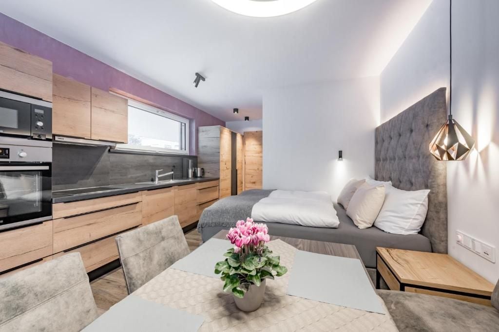 Een moderne keuken met houten kastjes, een inbouwoven en een eethoek met een tafel en stoelen.