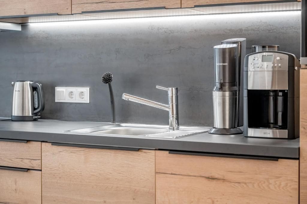 Eine moderne Küche mit einer Edelstahlspüle, einer Kaffeemaschine und einem Wasserkocher.