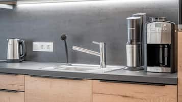 Eine moderne Küche mit einer Edelstahlspüle, einer Kaffeemaschine und einem Wasserkocher.