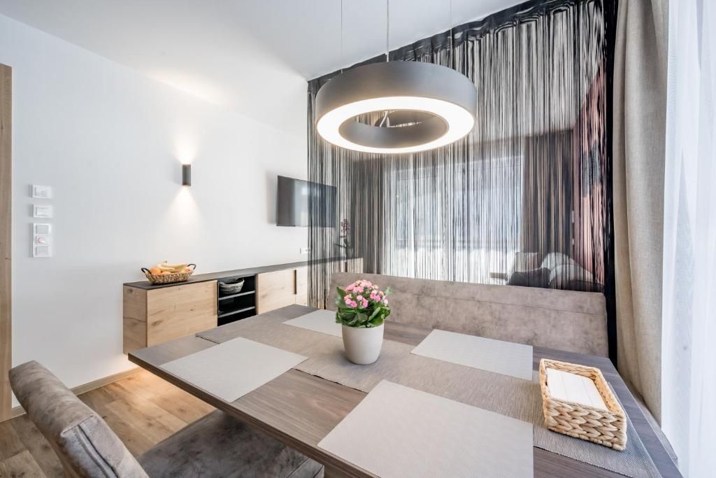 Un comedor moderno con una mesa de madera, un jarrón con flores y una lámpara colgante.