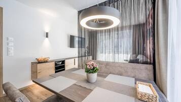 Un comedor moderno con una mesa de madera, un jarrón con flores y una lámpara colgante.