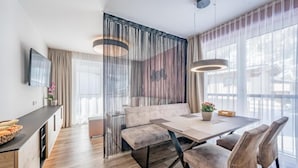 A modern dining area with a wooden floor, a central table, and a sofa. - MYALPS Jordans Lodge (Oberried)