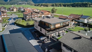 A modern hotel with a flat roof, surrounded by a green landscape and mountains in the background. - MYALPS Jordans Lodge (Oberried)